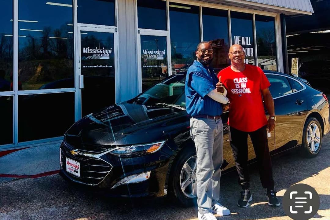 Customer and team member beside a black sedan